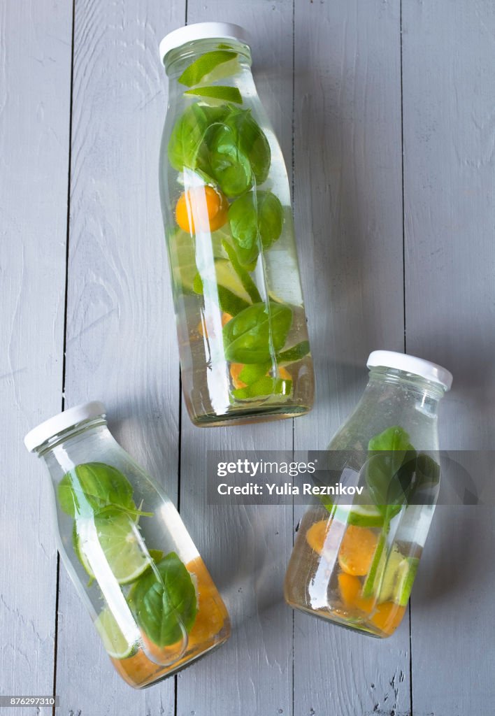 Three bottles of infused water with basil, physalis and sweet lime