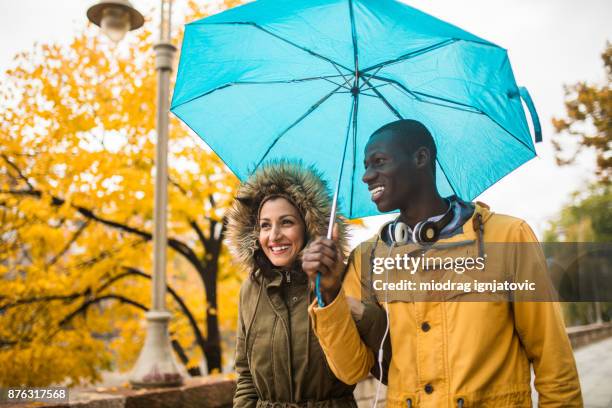 having fun on a rainy day - sharing umbrella stock pictures, royalty-free photos & images