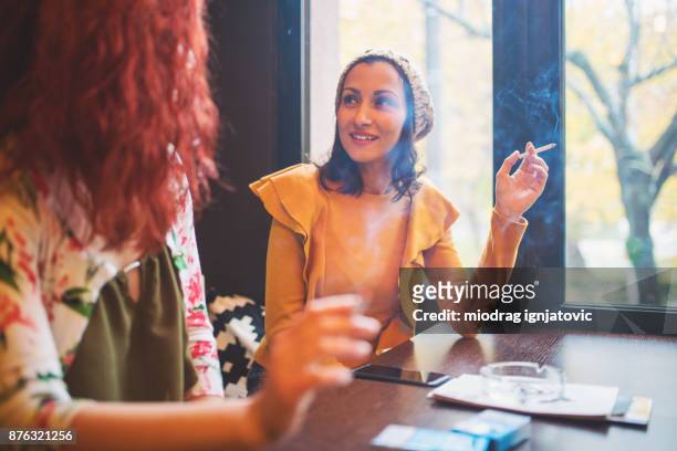 zwei junge frauen, die rauchen und spaß im café - woman smoking cigarette stock-fotos und bilder