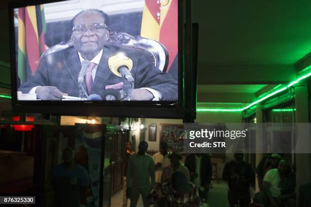 Zimbabweans watch a television broadcasting an address by President Robert Mugabe at Harare Sports Club in Harare on November 19 following a meeting...
