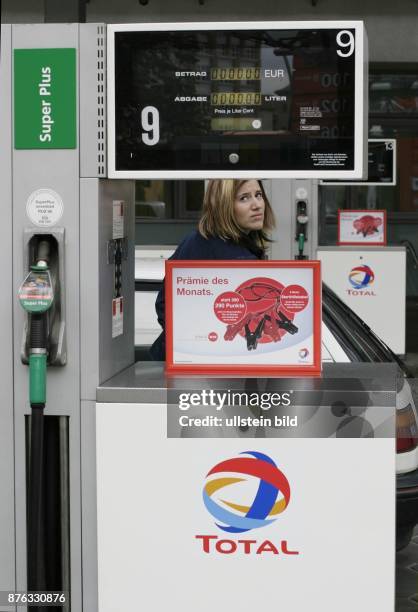 Autofahrerin schaut beim Tanken besorgt auf die Preisanzeige der Zapfsäule - 2003