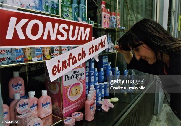 Eine Frau betrachtet die Auslagen im Schaufenster einer Drogerie in Leipzig - April 1991