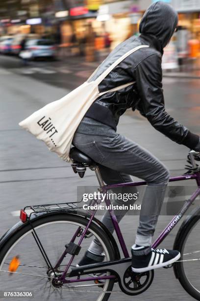 Deutschland Germany Berlin Radfahrerin mit Stofftasche überquert eine Strasse in der Hauptstadt.