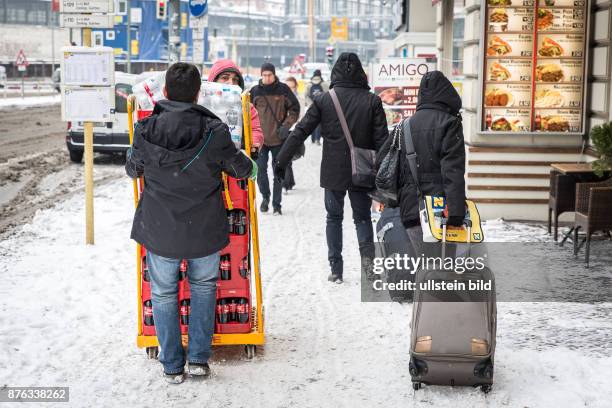 Deutschland Germany Berlin Reisende mit Rollkoffer passieren Getränkelieferanten auf einem schneebedeckten Bürgersteig Nähe Bahnhof Zoo.