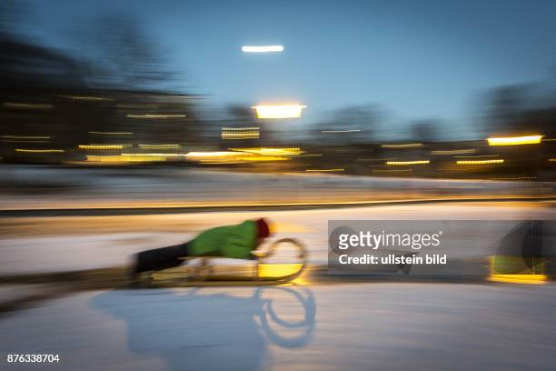 Deutschland Germany Berlin Ein Junge rutscht mit seinem Schlitten Ã¼ber eine gefrorene EisflÃ¤che im Weinbergspark in Berlin-Mitte.