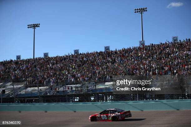 Fans look on as Dale Earnhardt Jr., driver of the AXALTA Chevrolet, drives during pace laps for the Monster Energy NASCAR Cup Series Championship...