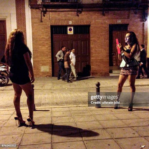 Spanien Andalusien Sevilla Junge Frauen fotografieren sich nachts auf einer Strasse mit dem Smartphone.