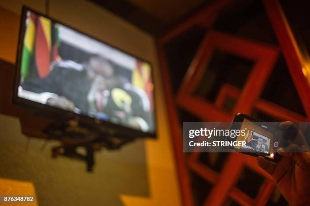 Man uses a mobile phone to record President Robert Mugabe's speech from a television while gathering at The Rainbow Towers in Harare on November 19,...