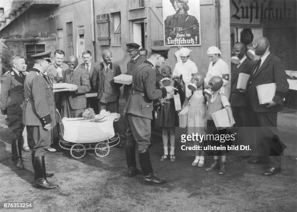 Angehörige des Reichsluftschutzbundes verteilen Gasmasken an Kinder und Erwachsene - 1937