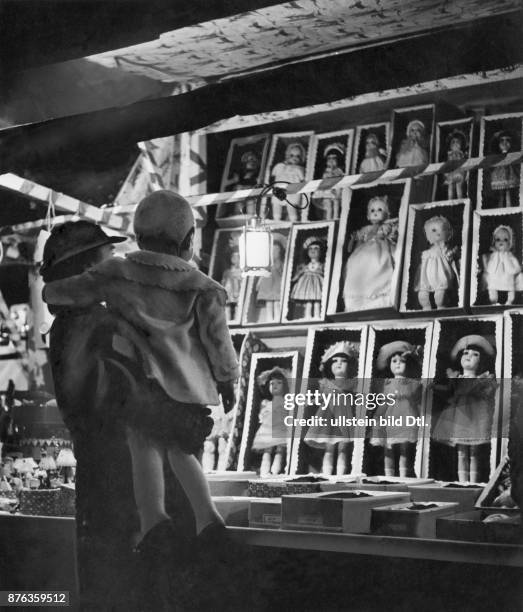 Würzburger Christkindlmarkt, Mutter und Kind betrachten die Auslage von Sonneberger Puppen erschienen in Dame 25/1940 Foto: Erika Schmachtenberger