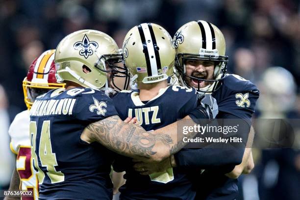 Wil Lutz is hugged by teammates Michael Hoomanawanui and Chase Daniels of the New Orleans Saints after kicking the winning field goal against the...