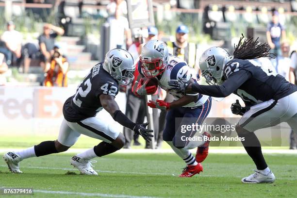 Dion Lewis of the New England Patriots splits a tackle from Karl Joseph and Reggie Nelson of the Oakland Raiders during the first half at Estadio...