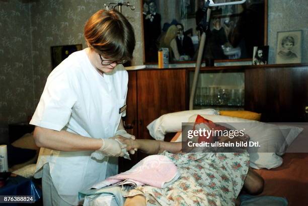 Pflegerin des Malteser Hilfsdienstes betreut eine bettlägerige Patientin - 1997