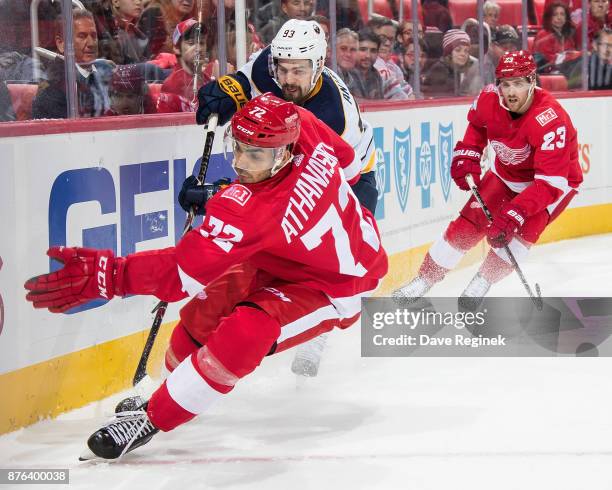 Andreas Athanasiou and Scott Wilson of the Detroit Red Wings work behind the net against Viktor Antipin of the Buffalo Sabres during an NHL game at...