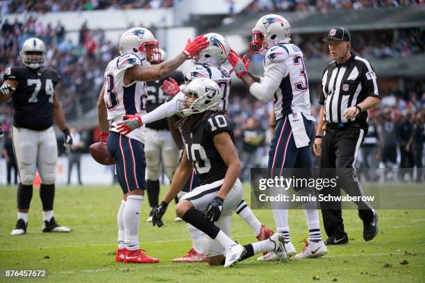 Patrick Chung, Jonathan Jones and Duron Harmon of the New England Patriots celebrate after stripping the ball from Seth Roberts of the Oakland...
