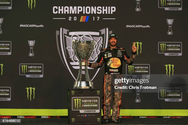 Martin Truex Jr., driver of the Bass Pro Shops/Tracker Boats Toyota, poses with the Monster Energy NASCAR Cup Series championship trophy after...