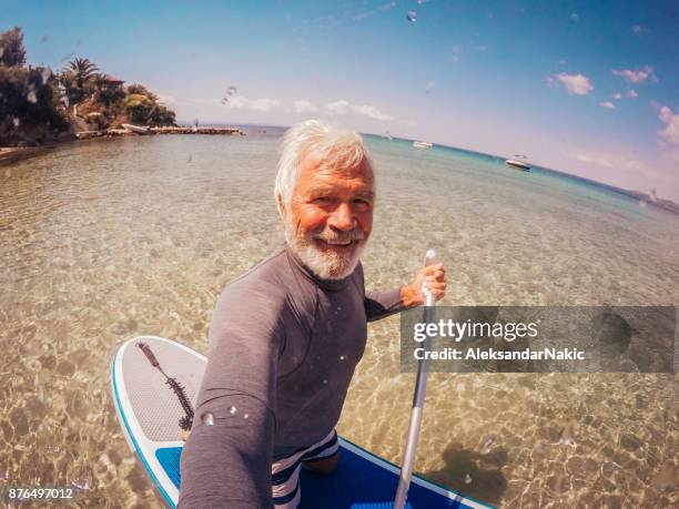selfie of a senior man ridding paddle board - paddle board men imagens e fotografias de stock