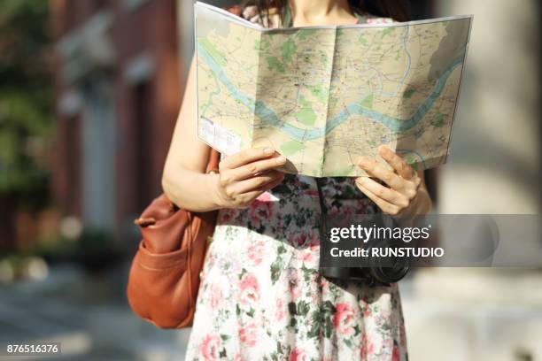 cropped image of woman holding map - frauen mit fotoapparat stock-fotos und bilder