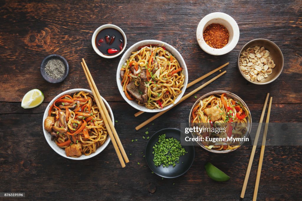Bowls with chicken, beef and vegetables chow mein and rice with pork