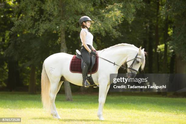 young woman riding on white horse - 乗馬帽 ストックフォトと画像