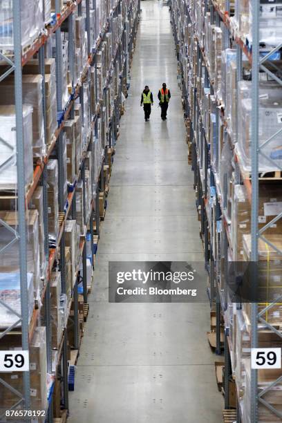 Workers walk through aisles of goods at the John Lewis Plc customer fulfilment and distribution centre in Milton Keynes, U.K., on Friday, Nov. 17,...