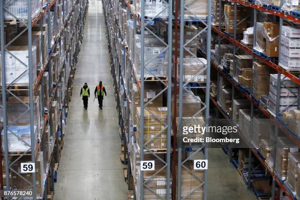 Workers walk through aisles of goods at the John Lewis Plc customer fulfilment and distribution centre in Milton Keynes, U.K., on Friday, Nov. 17,...