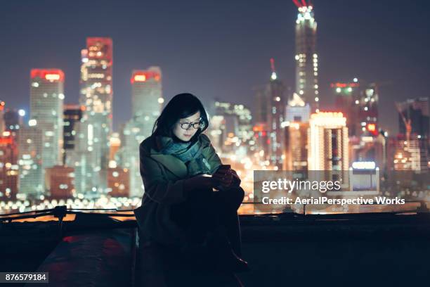 woman with smartphone standing on skyscraper roof - peking skyline stock pictures, royalty-free photos & images