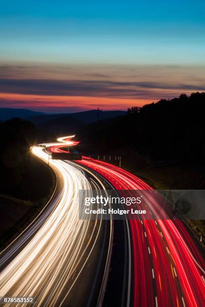 car light streaks on autobahn a3 motorway connecting würzburg and frankfurt at dusk, weibersbrunn, spessart-mainland, franconia, bavaria, germany - autobahn germany stock pictures, royalty-free photos & images