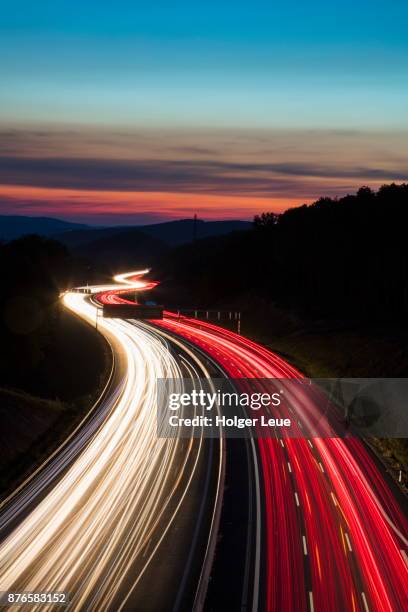 car light streaks on autobahn a3 motorway connecting würzburg and frankfurt at dusk, weibersbrunn, spessart-mainland, franconia, bavaria, germany - vehicle light stock pictures, royalty-free photos & images
