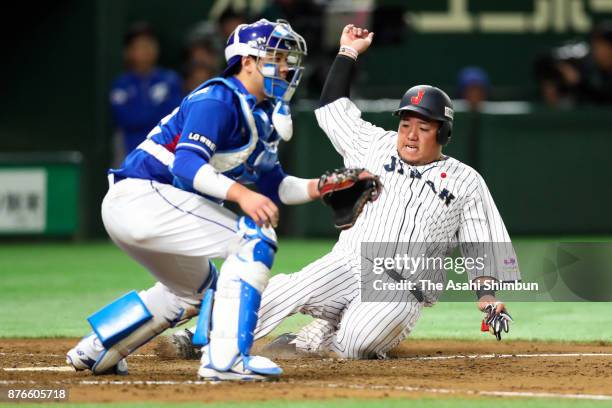 Infielder Hotaka Yamakawa of Japan slides into the home plate to score a run to make it 1-0 by the RBI double of Infielder Shuta Tonosaki in the...