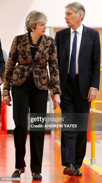 Britain's Prime Minister Theresa May and Britain's Chancellor of the Exchequer Philip Hammond react during a visit an engineering training facility...