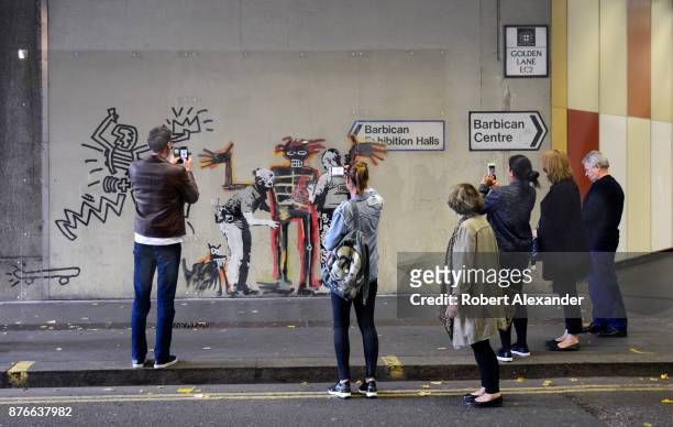 Londoners and visitors admire and photograph street art created in September 2017 near the Barbican Centre in London, England, by Banksy, an...