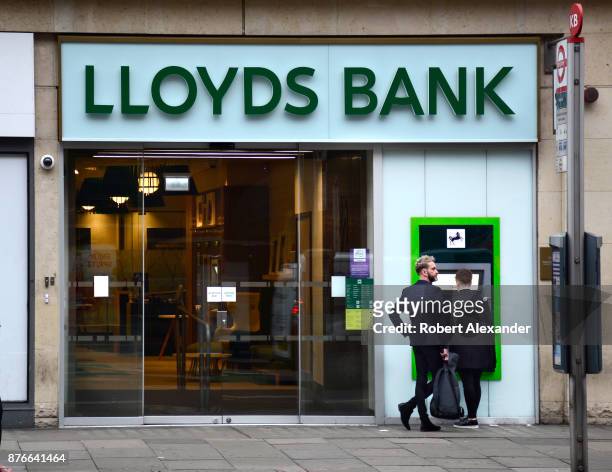 Banking customers use an ATM machine at a Lloyds Bank in London, England. Lloyds Bank is a British retail and commercial bank with branches across...