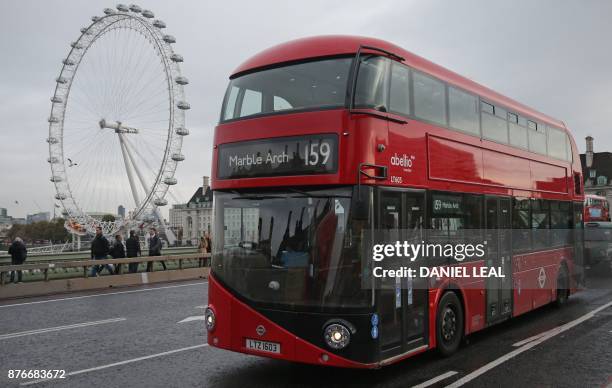 Red London double-decker bus passes the London Eye as it is driven over Westminster Bridge in central London on November 20, 2017. - London's...