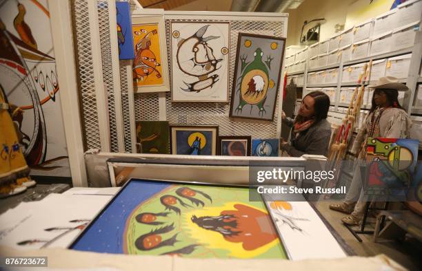 Anong Beam pulls out one of the screens that store paintings. Art, artifacts and other historical items are stored In the Foundation's storage area....