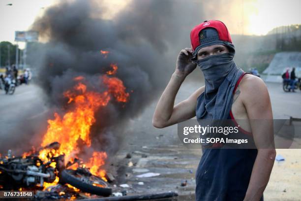 An anti-government demonstrator stands by a burning motorcycle protesters took away from National Guards who blocked them from marching to the office...