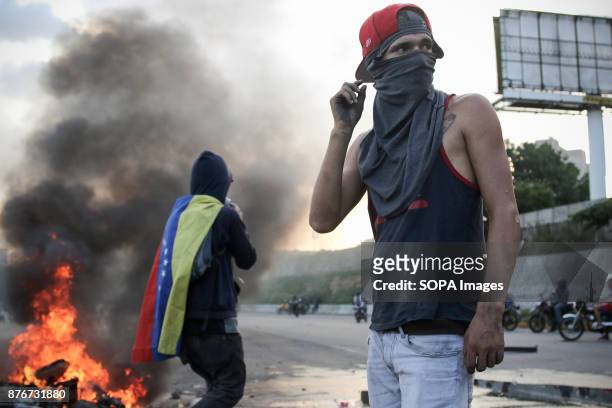 An anti-government demonstrator stands by a burning motorcycle protesters took away from National Guards who blocked them from marching to the office...