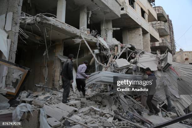 People inspect the debris of a building after Assad regime's warcrafts carried out airstrikes over residential areas of Kafr Batna town of the...