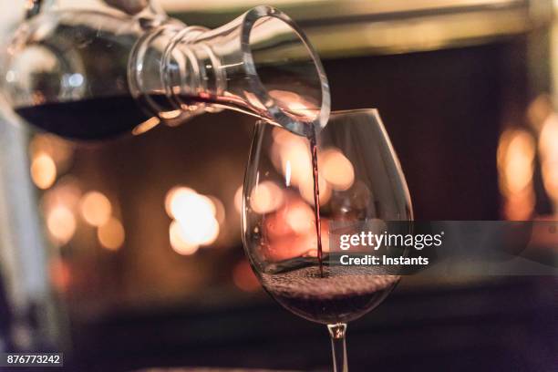 unrecognizable woman, a decanter in her hands, pouring red wine in a glass. - carafe stock pictures, royalty-free photos & images