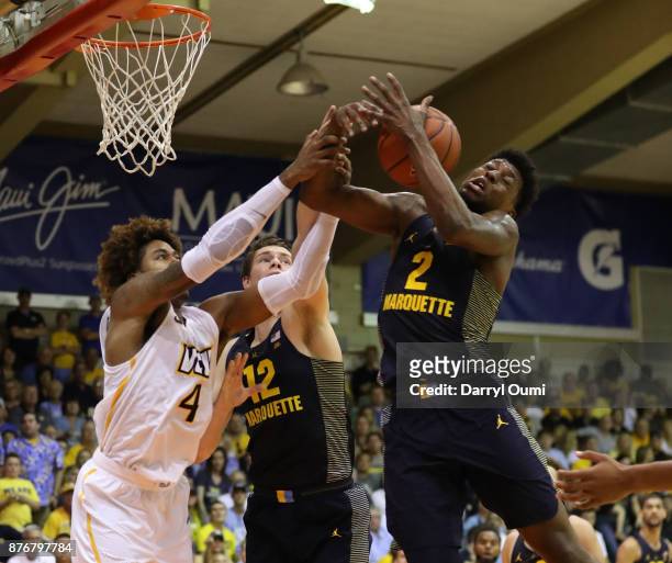 Sacar Anim and Matt Heldt of the Marquette Golden Eagles battle with Justin Tillman of the VCU Rams for a rebound during the first half of their game...
