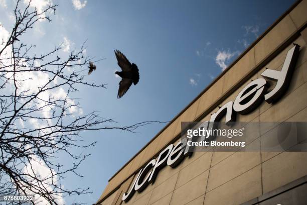 Birds fly past J.C. Penney Co. Signage displayed outside a store in the Queens borough of New York, U.S., on Monday, Nov. 20, 2017. Traditional...