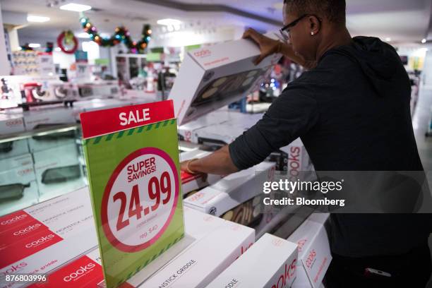 An employee arranges boxes of griddle pans on display for sale at a J.C. Penney Co. Store in the Queens borough of New York, U.S., on Monday, Nov....