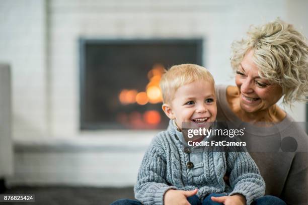 auf mamas schoß sitzen - kaminfeuer stock-fotos und bilder