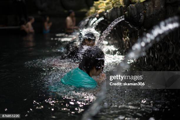 pilgrim and hindu people come to holy dip at the tirta empul temple on april 10, 2017 in bali, indonesia. - tirta empul temple stock pictures, royalty-free photos & images