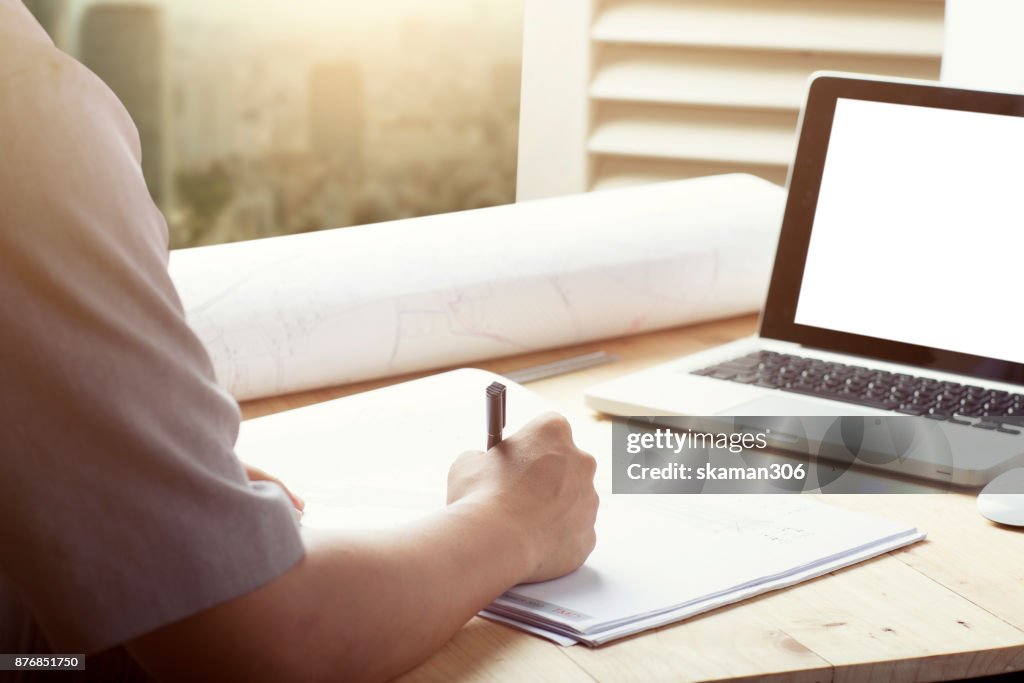 Close-up hand Of male Architect Drawing Blueprint on work space wooden table in office