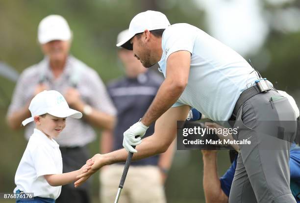 Jason Day of Australia high fives with 5 year old golfer Isaac Riches during a practice round ahead of the 2017 Australian Open at The Australian...