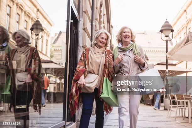 sozialer senioren. frauen in führungspositionen shoppen, spaß haben und lachen auf der straße - girlfriend stock-fotos und bilder