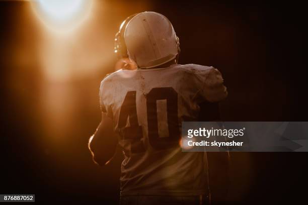 rear view of american football player at sunset. - american football uniform stock pictures, royalty-free photos & images