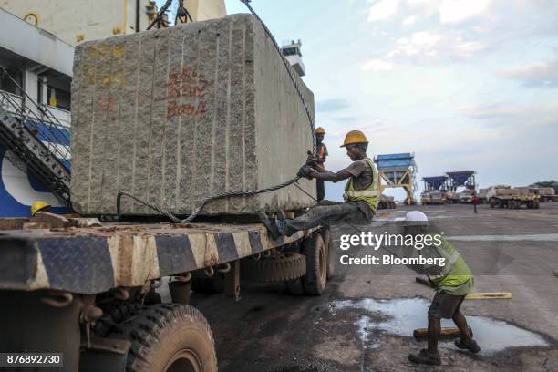 Workers secure a wire rope while loading a block of limestone from a truck to the Da Dan Xia cargo ship at Krishnapatnam Port in Krishnapatnam,...