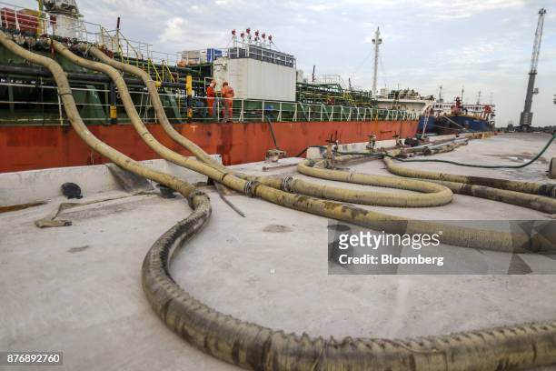Workers supervise edible oil being moved while working on the Gandawati Tarawa tanker docked at Krishnapatnam Port in Krishnapatnam, Andhra Pradesh,...